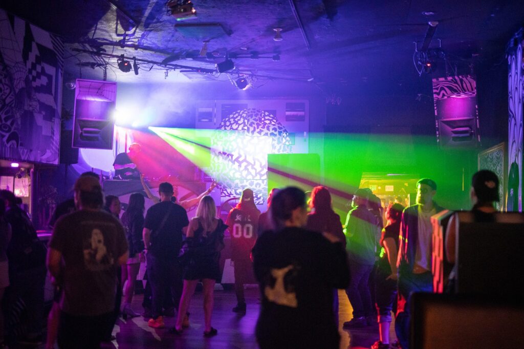 Crowd dancing under green and pink lasers at PULSE in Denver, Oct 10, 2026